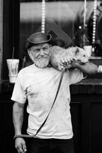 grayscale photography of a man carrying dog